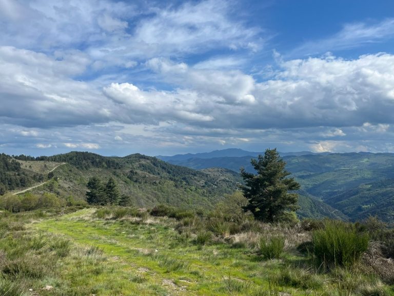 Paysage montagneux avec des collines verdoyantes et un ciel nuageux.