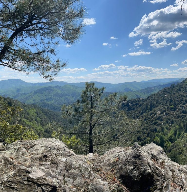 Vue panoramique des montagnes verdoyantes sous un ciel partiellement nuageux.